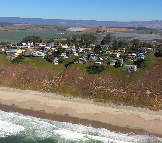 View of homes above the beach with farmland in the background