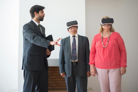 Couple with realtor looking through Virtual Reality technology at homes