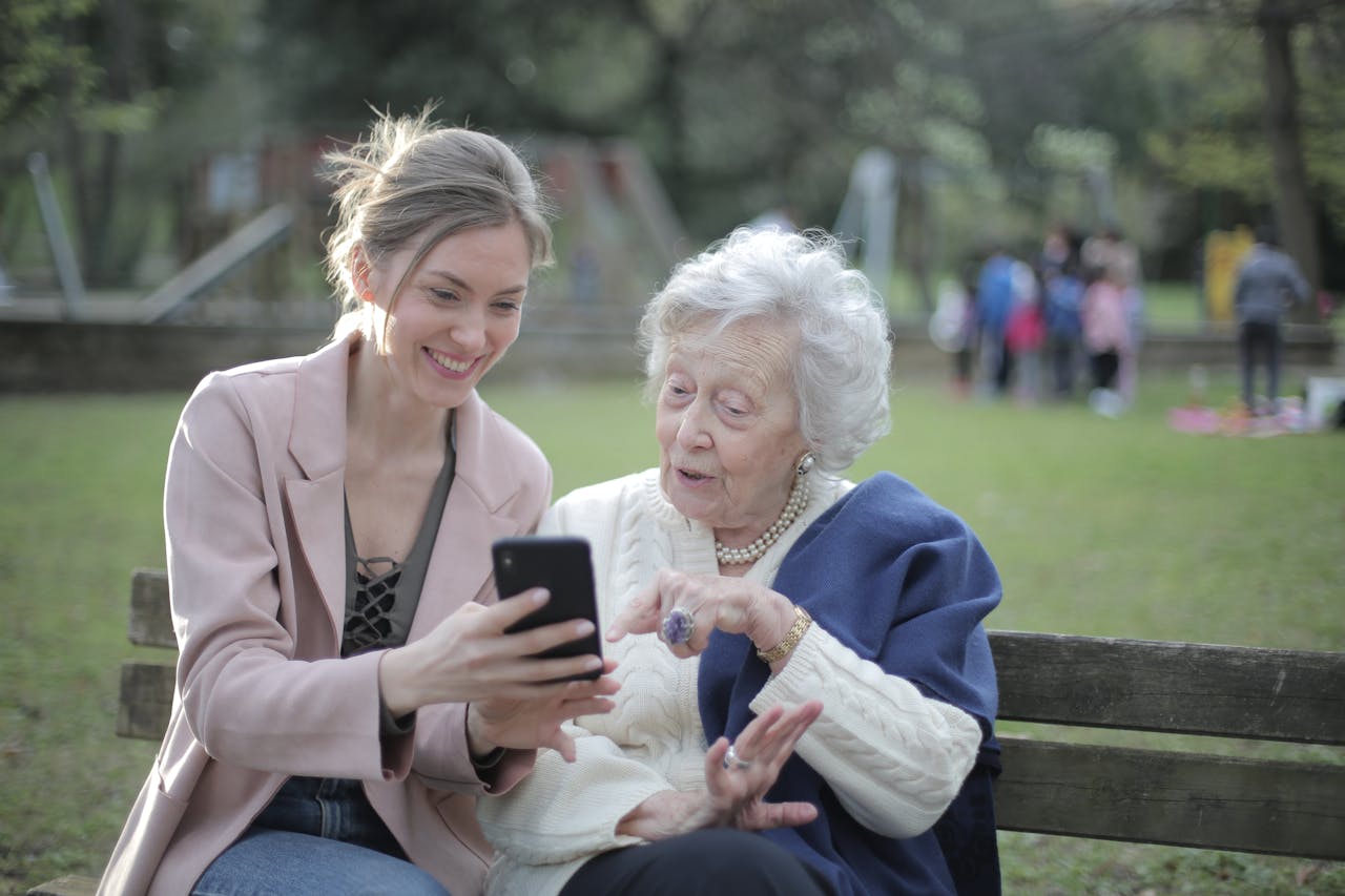 Grandmother and niece looking at cell phone in a park