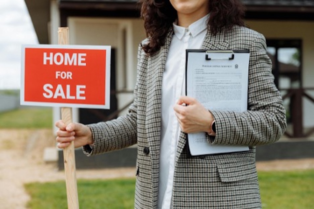 women holding home for sale sign
